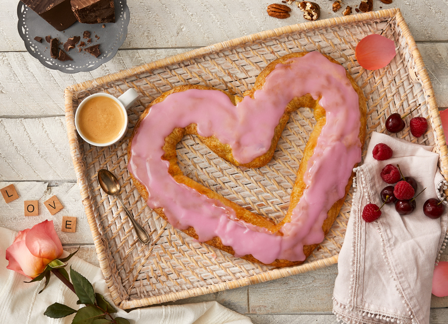 Pink heart-shaped Kringle on a breakfast tray and roses on the side. 