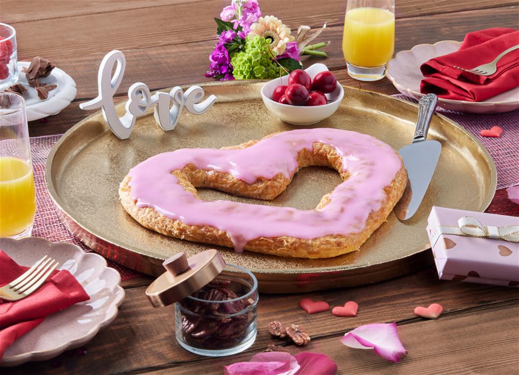 Heart Shaped Kringle on a gold tray surrounded by flower, petals, and ingredients. 