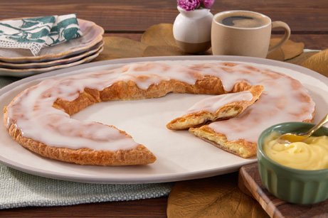 Bavarian Creme Kringle on a white plate with slices cut out. 