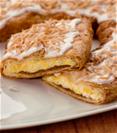 Coconut Kringle of a white plate with coconut shavings and coconut halves. 
