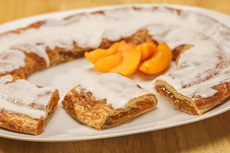 Apricot Kringle on white plate with apricot slices. 