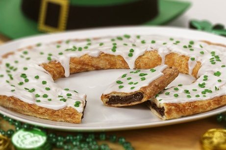 St. Patrick's Day Kringle on white plate with green beads, coins and green top hat. 
