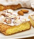 Almond Kringle sitting on a white plate with a few almonds next to the Kringle. 