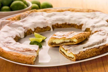 Key Lime Kringle on a white plate with slices of limes and bowl of limes. 