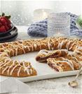 Merry Berry Kringle on white plate with bowl of mixed berries and surrounded by winter holiday items. 