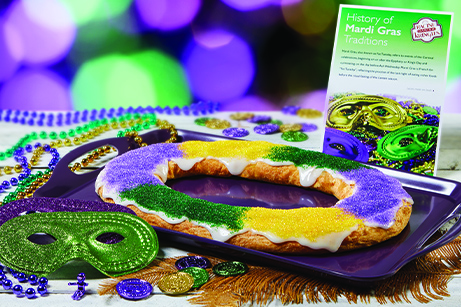 Mardi Gras Kringle on purple tray with history card, bead necklaces, mask, coins in mardi gras colors.