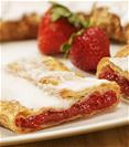 Strawberry Kringle on a white plate with sliced and whole strawberries. 