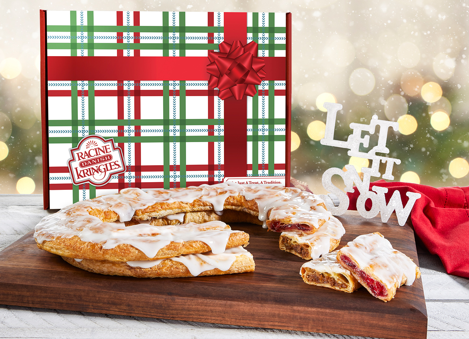 Holiday Gift box with red bow in artwork with raspberry and pecan Kringle in front on plate