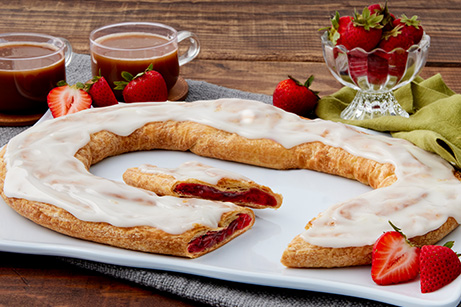 Strawberry Kringle on a white plate with sliced and whole strawberries. 