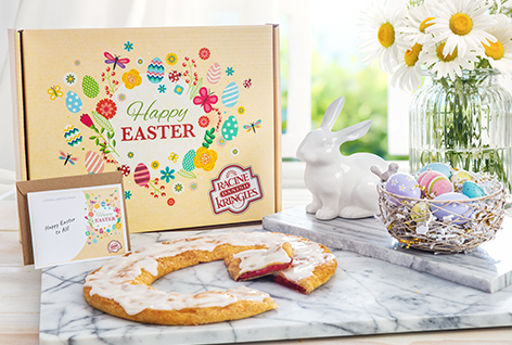 Yellow Easter Gift box with Kringle in front surrounded by Easter decorations and daisies in vase. 