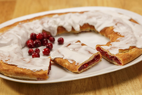 Cranberry Kringle on white plate with a scattering of cranberries. 