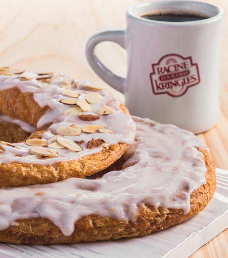Two Kringle on a white platter with a mug of coffee
