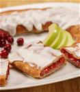 Cranberry Apple Kringle on white plate with apple slices and scattering of cranberries. 