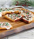 Santa's Cinnaberry Kringle on wood board with bowl of cranberries, cinnamon sticks and festive pine branch. 