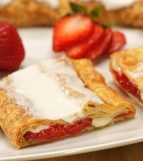 Strawberry Cheesecake Kringle on a white plate with slices strawberries. 