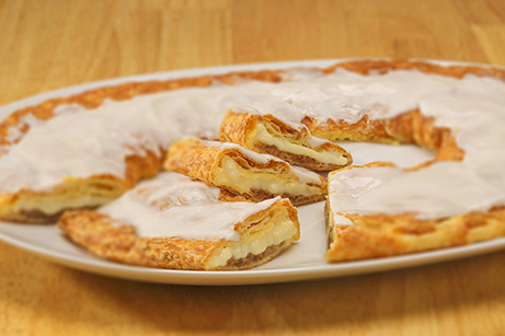 Bavarian Creme Kringle on a white plate with slices cut out. 