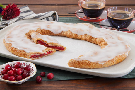 Cranberry Kringle on white plate with a scattering of cranberries. 