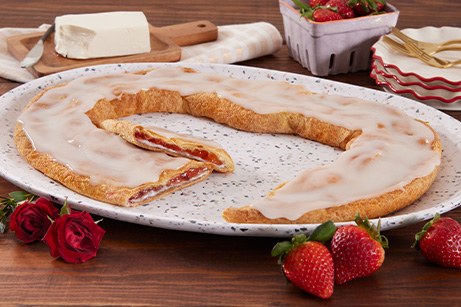Strawberry Cheesecake Kringle on a white plate with slices strawberries. 