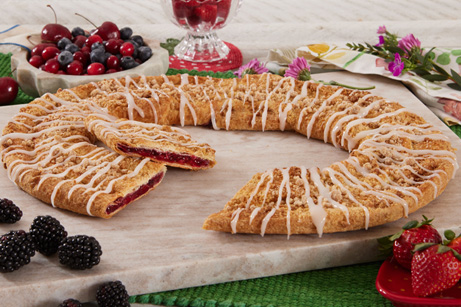 Berry Crumble Kringle on white plate with mixed berries.