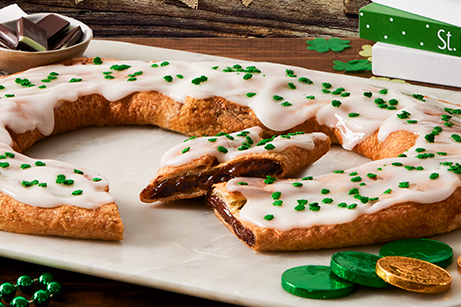 St. Patrick's Day Kringle on white plate with green beads, coins and green top hat. 