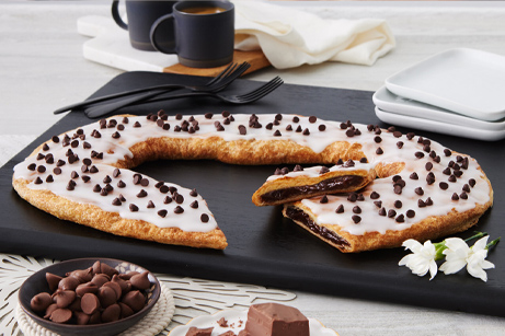 Chocolate Chip Kringle on white plate with chunks of chocolate. 