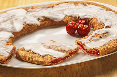 Cherry Kringle on white plate with a few cherries. 