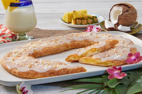 Pina Colada Kringle on a white plate with pineapple and coconut next to the kringle.